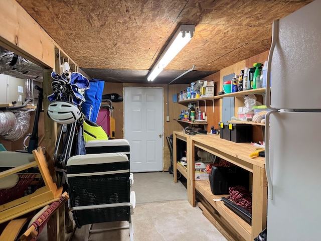 basement with a workshop area and freestanding refrigerator