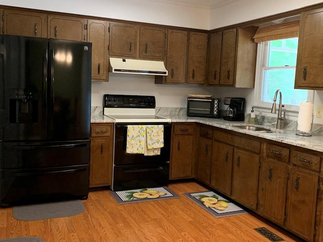 kitchen with light stone countertops, black refrigerator with ice dispenser, sink, light hardwood / wood-style floors, and white range with electric cooktop