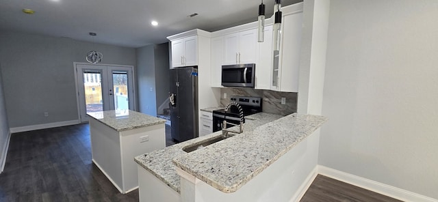 kitchen with kitchen peninsula, white cabinets, stainless steel appliances, and a kitchen island