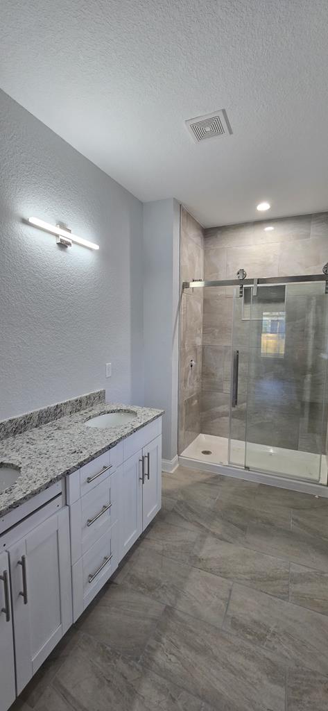 bathroom featuring vanity, a shower with shower door, and a textured ceiling