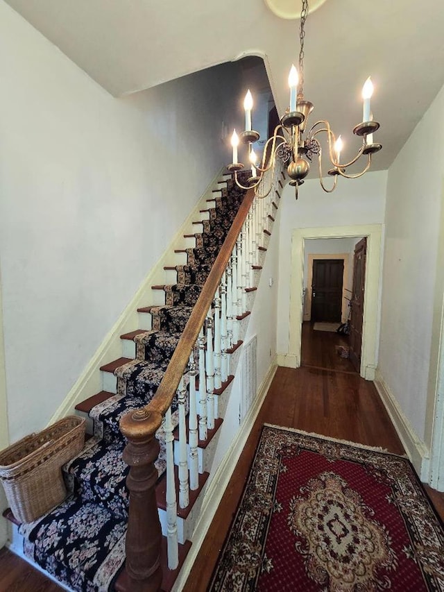 stairs with a chandelier and hardwood / wood-style flooring