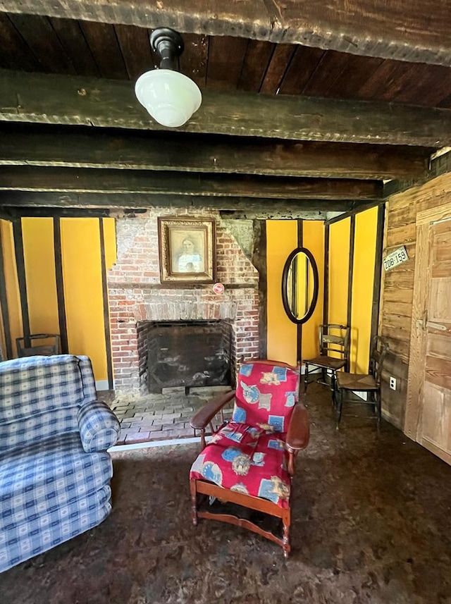 carpeted living room featuring beam ceiling, a fireplace, and wooden walls