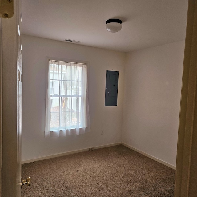 carpeted spare room featuring visible vents, electric panel, and baseboards