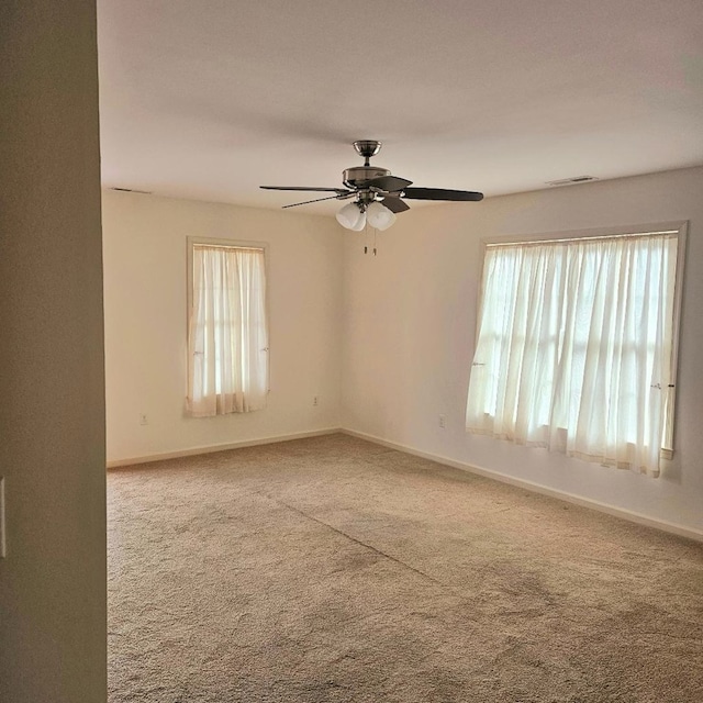 carpeted spare room with plenty of natural light, visible vents, and baseboards