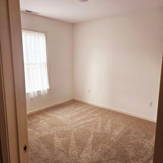 carpeted empty room with plenty of natural light, visible vents, and baseboards