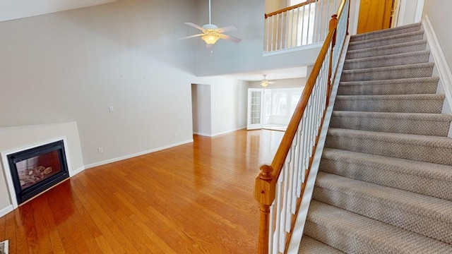 stairway featuring wood-type flooring, high vaulted ceiling, and ceiling fan