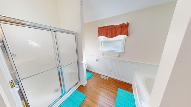 bathroom with hardwood / wood-style flooring, toilet, and plus walk in shower