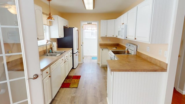 kitchen featuring white appliances, sink, hanging light fixtures, light hardwood / wood-style flooring, and white cabinetry