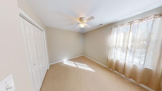 unfurnished bedroom featuring ceiling fan, light carpet, and a closet