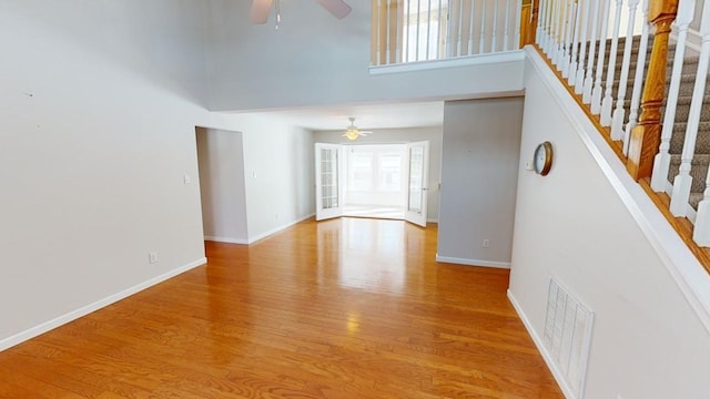 spare room featuring a towering ceiling, light hardwood / wood-style flooring, and ceiling fan