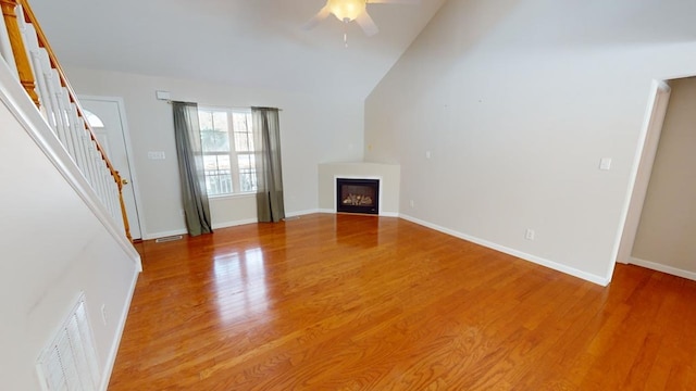 unfurnished living room with hardwood / wood-style flooring, vaulted ceiling, and ceiling fan