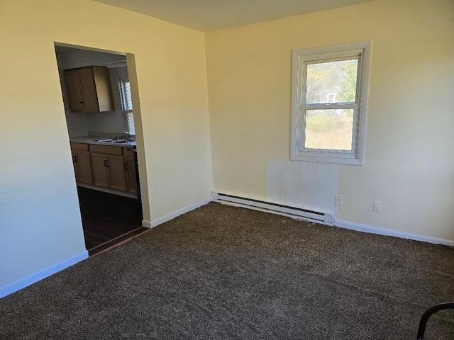 carpeted empty room featuring sink and baseboard heating
