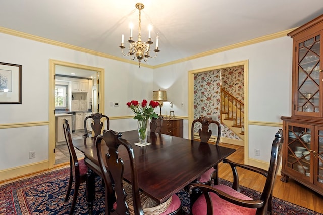 dining room with ornamental molding, light wood-type flooring, and a notable chandelier