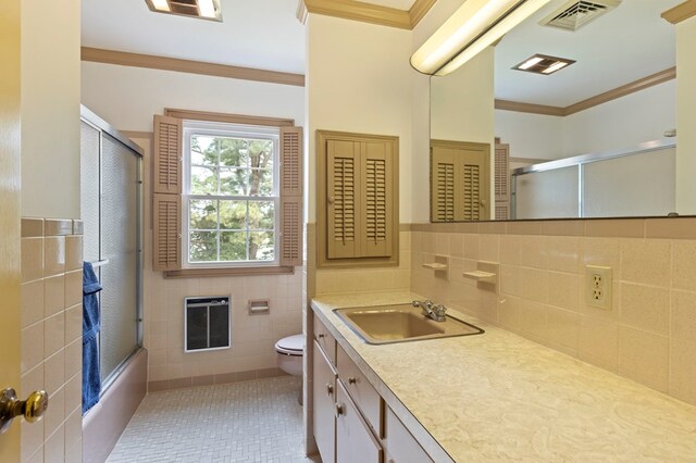 full bathroom featuring tile patterned floors, bath / shower combo with glass door, vanity, heating unit, and tile walls