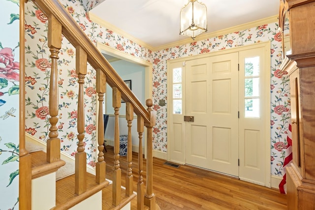 entryway featuring wood-type flooring, an inviting chandelier, and ornamental molding