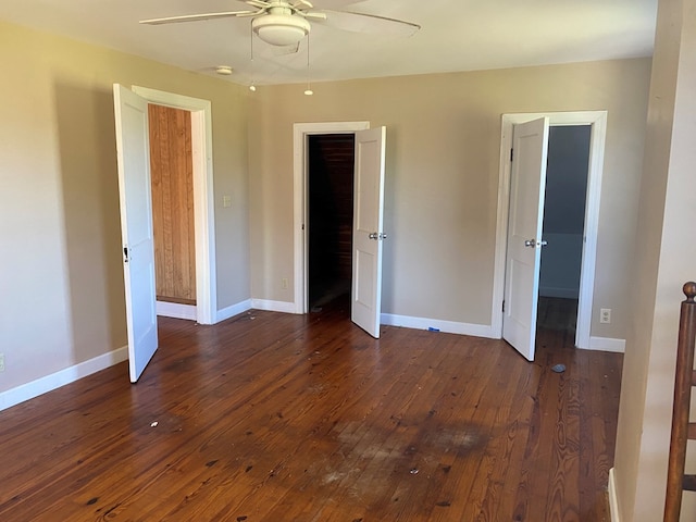 unfurnished bedroom with a closet, a walk in closet, ceiling fan, and dark hardwood / wood-style flooring