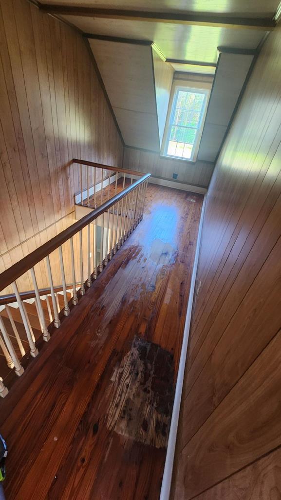 stairway with hardwood / wood-style flooring and wood walls