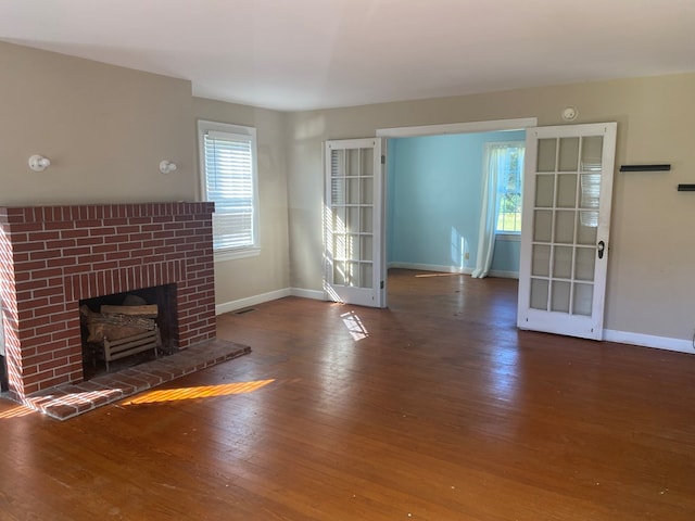 unfurnished living room with dark hardwood / wood-style flooring, a fireplace, and french doors