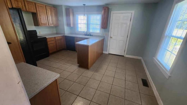 kitchen with light tile patterned floors, black electric range oven, a healthy amount of sunlight, and decorative light fixtures