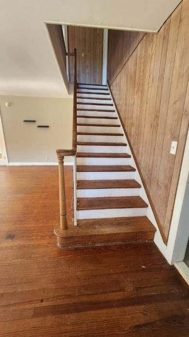 stairway with wood walls and wood-type flooring