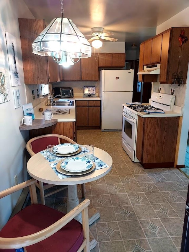 kitchen with ceiling fan with notable chandelier, pendant lighting, and white appliances