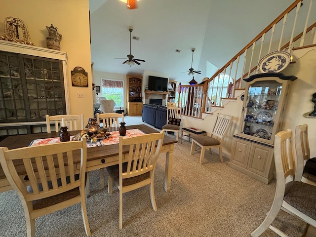 20444 Baldpate Ln, Onancock, VA 23417 - carpeted dining room with high vaulted ceiling, ceiling fan, a fireplace, and stairway