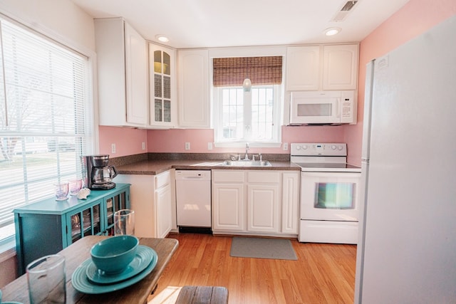 kitchen with visible vents, a sink, white cabinetry, white appliances, and light wood finished floors