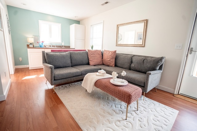 living room with light wood-style flooring, baseboards, and visible vents