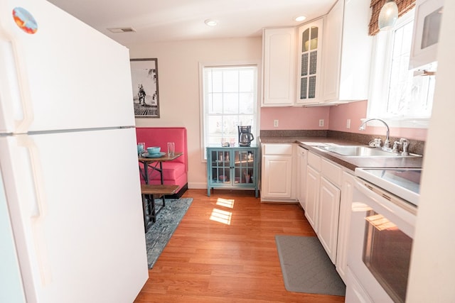 kitchen featuring light wood-style flooring, white appliances, white cabinets, and a sink