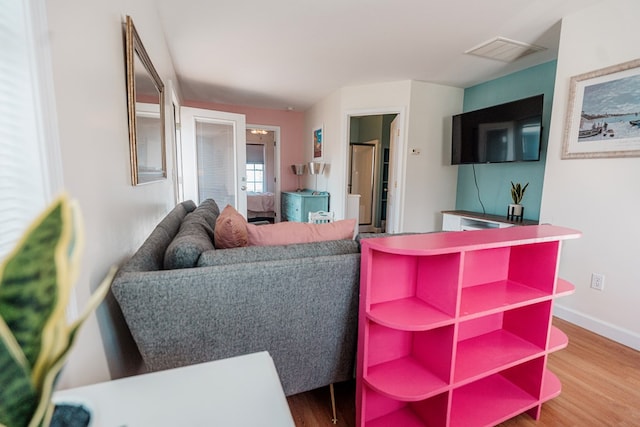 living area featuring visible vents, baseboards, and wood finished floors