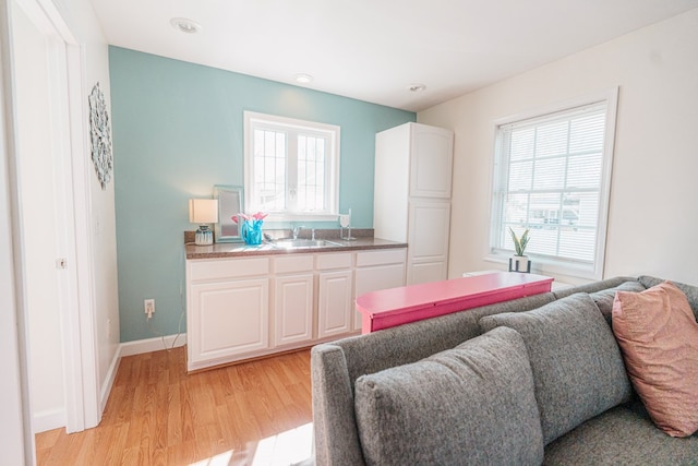 bedroom with baseboards, light wood-type flooring, and a sink