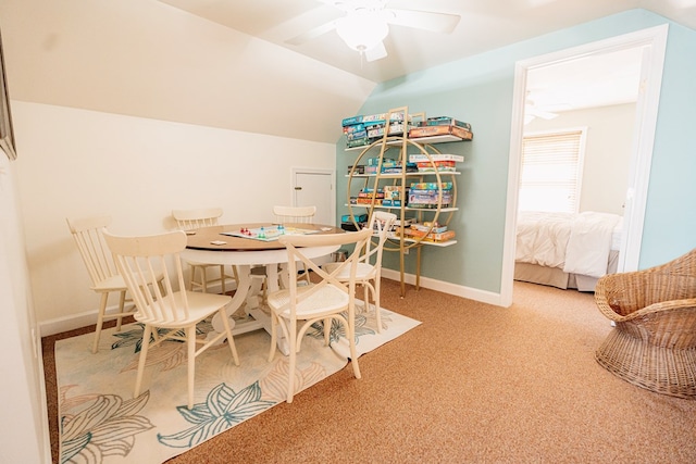 carpeted dining space with lofted ceiling, baseboards, and ceiling fan