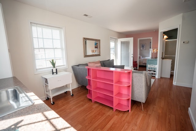 living room with light wood-style floors, visible vents, and baseboards