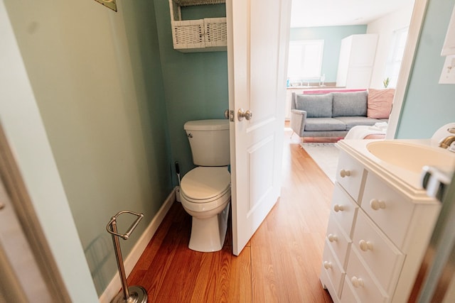 bathroom featuring toilet, vanity, baseboards, and wood finished floors