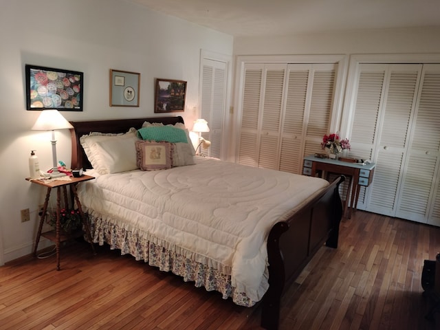 bedroom featuring wood-type flooring and two closets