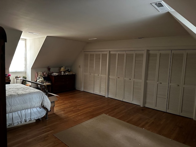 bedroom featuring hardwood / wood-style floors, two closets, and lofted ceiling