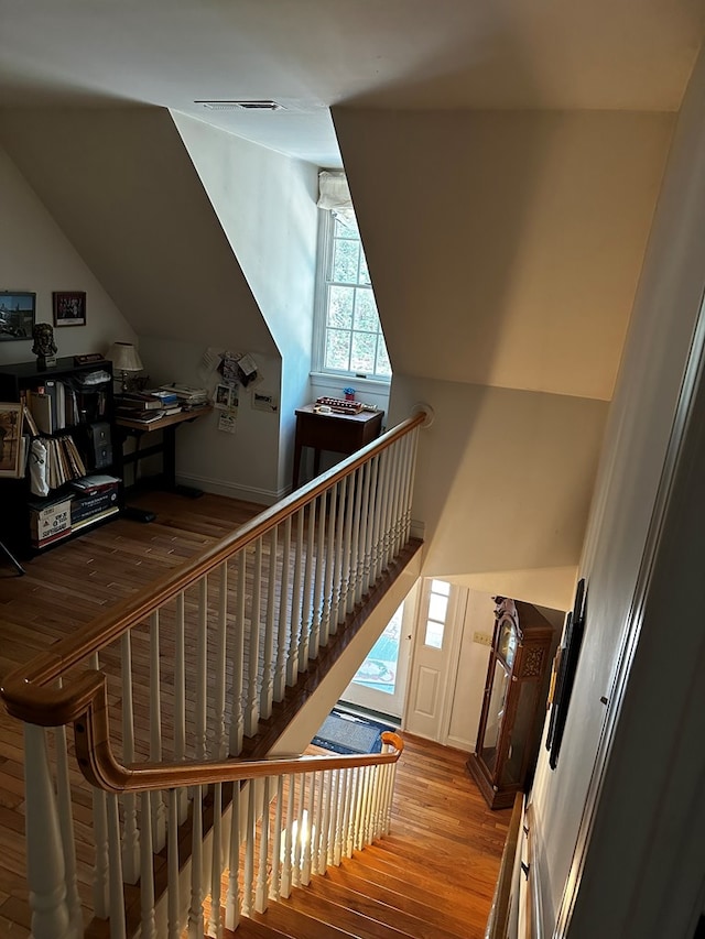 stairway featuring hardwood / wood-style floors and vaulted ceiling