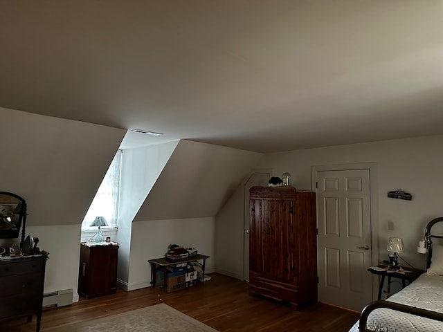 bedroom featuring dark hardwood / wood-style floors, vaulted ceiling, and a baseboard heating unit