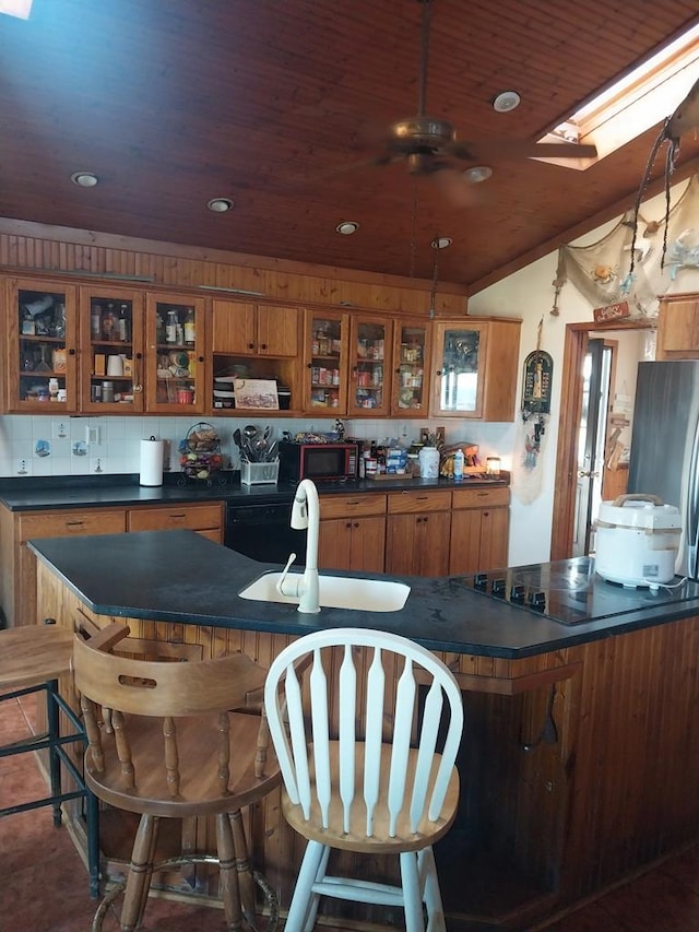 kitchen featuring sink, a kitchen breakfast bar, tasteful backsplash, lofted ceiling with skylight, and wood ceiling