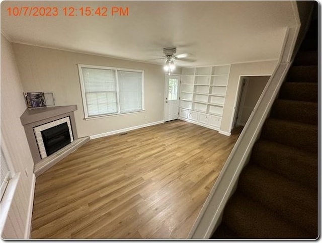 unfurnished living room featuring ceiling fan, built in features, and hardwood / wood-style flooring