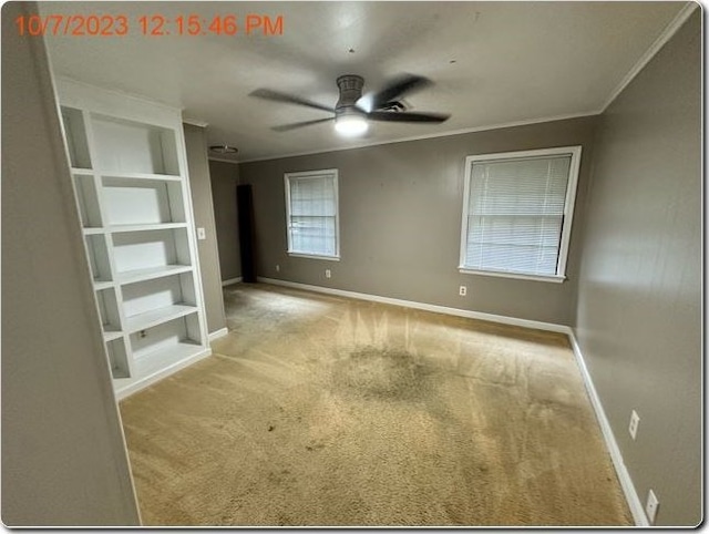 carpeted empty room featuring built in shelves and ceiling fan