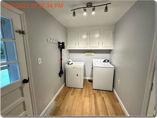 clothes washing area featuring cabinets, light hardwood / wood-style flooring, and washing machine and clothes dryer