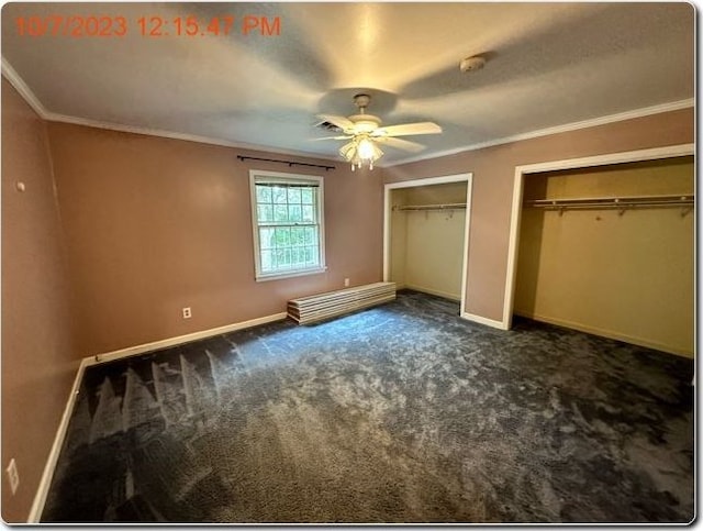 unfurnished bedroom with dark carpet, multiple closets, ornamental molding, and ceiling fan