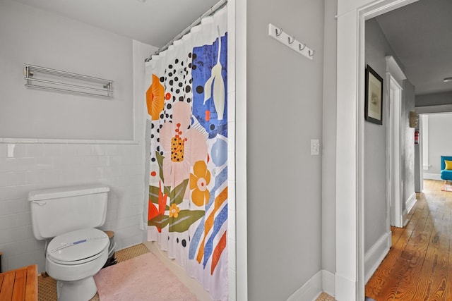 4282 Main St, Chincoteague, VA 23336 - bathroom featuring curtained shower, tile walls, wood finished floors, and wainscoting