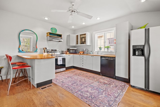 4282 Main St, Chincoteague, VA 23336 - kitchen featuring black appliances, white cabinetry, light wood-type flooring, recessed lighting, and glass insert cabinets