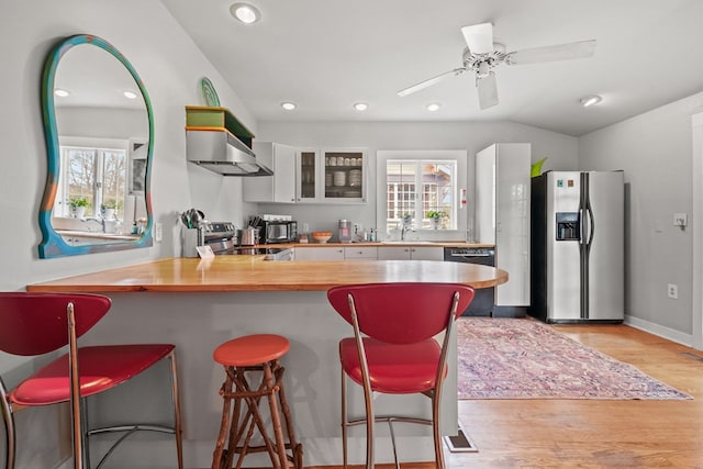 4282 Main St, Chincoteague, VA 23336 - kitchen featuring stainless steel appliances, ventilation hood, wooden counters, a breakfast bar area, and light wood finished floors