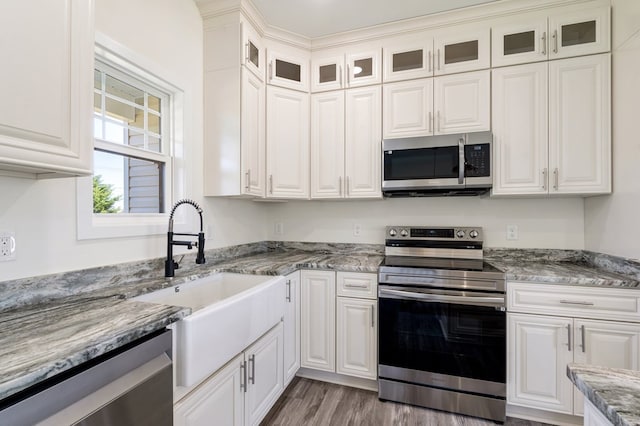 kitchen with sink, light hardwood / wood-style flooring, light stone countertops, white cabinetry, and stainless steel appliances