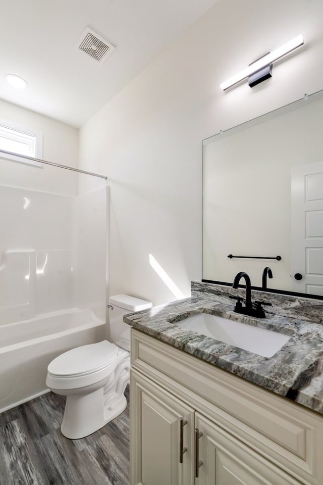 full bathroom featuring washtub / shower combination, hardwood / wood-style floors, vanity, and toilet