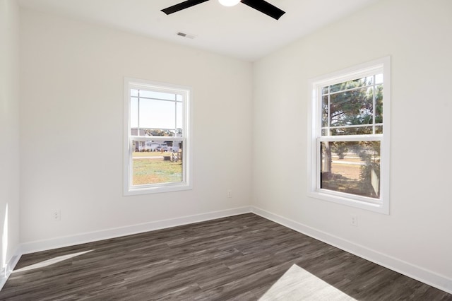 empty room featuring ceiling fan, plenty of natural light, and dark wood-type flooring