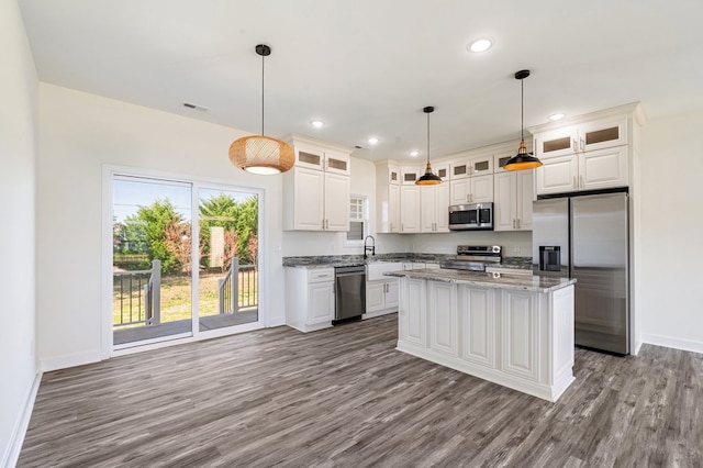 kitchen with light stone countertops, appliances with stainless steel finishes, pendant lighting, light hardwood / wood-style flooring, and a center island